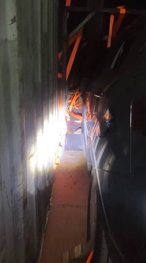 Side view of a vehicle inside a container with orange securing straps