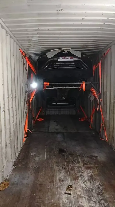 Container interior showing a vehicle, loading rack and orange securing straps